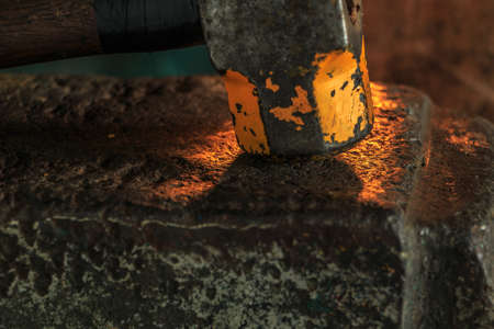 The blacksmith manually forging the molten metal on the anvil in smithyの写真素材