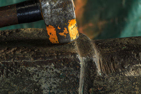 The blacksmith manually forging the molten metal on the anvil in smithy