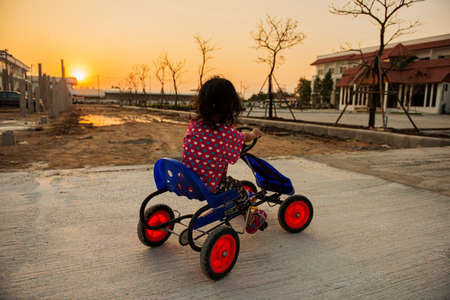 cute little curly girl riding a four wheel bicycleの写真素材