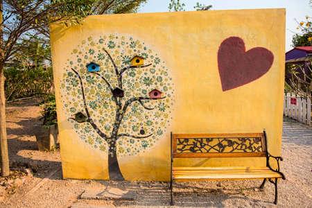 art tree painting on cement wall and yellow park bench.の写真素材