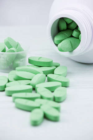 Green pills an pill bottle on the table.の写真素材