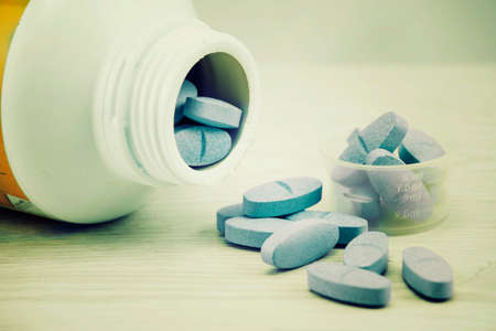 Blue pills an pill bottle on the table. Vintage tone.の写真素材