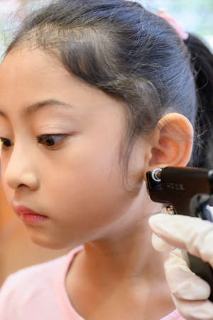 Adorable little Asian girl having ear piercing process.の写真素材
