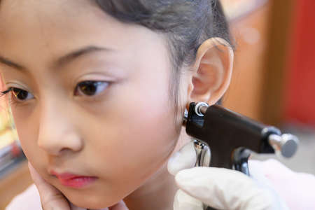 Adorable little Asian girl having ear piercing process.の写真素材