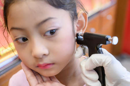 Adorable little Asian girl having ear piercing process.の写真素材