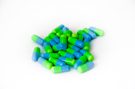 Green and blue capsules medicine on white background