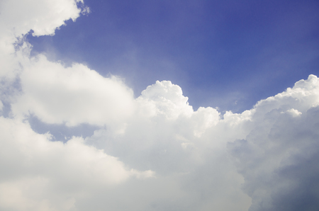 Blue sky and puffy white clouds with brightness from sunの写真素材