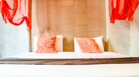 Beautiful vintage bedroom with pink pillow , red mosquito net and thai style scravesの写真素材