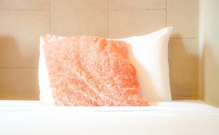 Pink and white puff pillows on white bedの写真素材