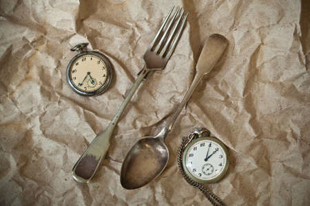 Vintage silver cutlery and antique clock on vintage backgroundの写真素材