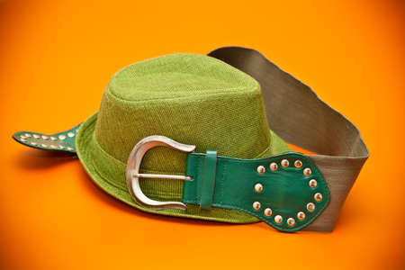 Green hat and a green belt with a buckle in western style on an orange backgroundの写真素材