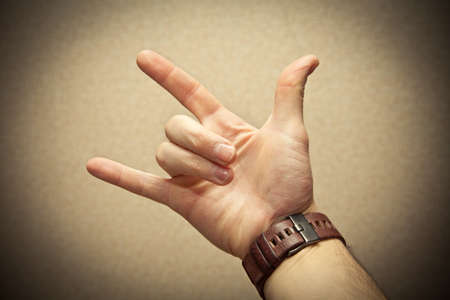Fingers to show metal goat. watch on hand. photo toned yellow