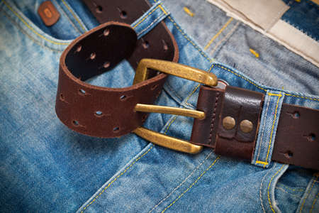 Tighten the leather belt with a buckle on jeansの写真素材