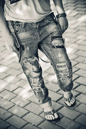 Female figure close-up - ripped jeans worn with suspenders, shirt, sandals, a bracelet on her arm
