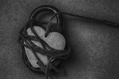 Heart on the lock. Conceptual photo of a symbolic heart with a rope tied to the hanging padlockの写真素材