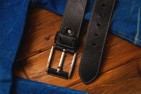 leather belt with buckle and jeans fabric on a wooden backgroundの写真素材