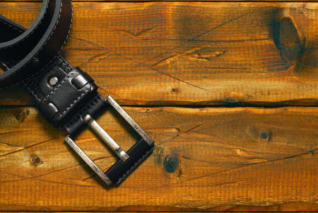 black strap with buckle on the old wooden background. Free space on the backgroundの写真素材