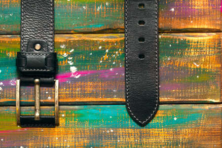 Leather trouser with a buckle on a multicolored wooden backgroundの写真素材
