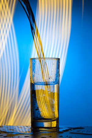 A jet of water pours into the glass. Double exposureの写真素材