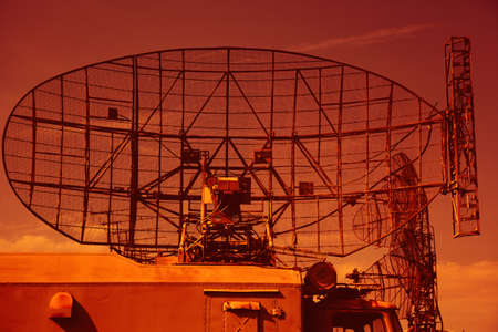 Military radar on the roof of a military vehicle. Military locator on a bright sky backgroundの写真素材
