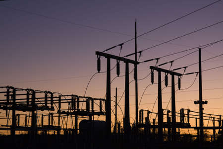 Silhouette of electric power lines and power station at sunsetの写真素材
