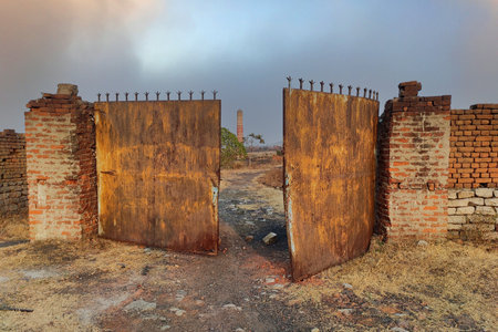 The old outer wall and broken iron gate of an abandoned factory which carries the tradition of the...