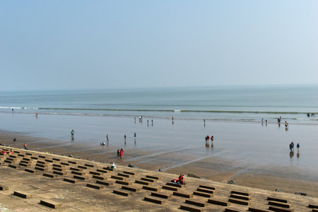 This is a high-angle view of the scenic beach of Digha, where people are bathing and wading in the calm ocean, which stretches to the horizon and merges seamlesslyの写真素材