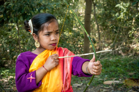 An Indigenous young girl in a vibrant traditional outfit with golden earrings and a pearl hair...