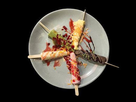 High angle view of delicious ice creams is beautifully decorated on a white ceramic plate. Isolated on black background.の写真素材