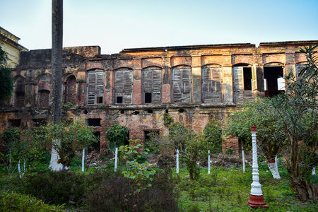 The image showcases the abandoned, weathered Nasipur Palace from the colonial era in Murshidabad, India. Its brick walls and wooden shutters tell stories of the past. Time has gently eroded its faÃ§adeの写真素材