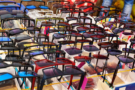 A vibrant array of stylish sunglasses is beautifully displayed in neat rows, each pair capturing the various sunlight colours and making this market stall a kaleidoscope of fashion and summer vibes.の写真素材