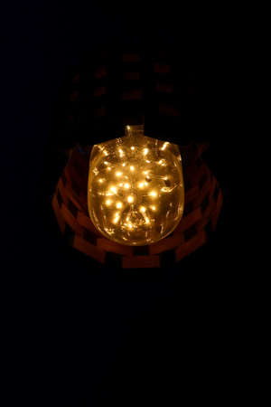 aesthetic, bright, vintage LED lamp with interconnected orange-yellow LED cluster isolated in a dark...