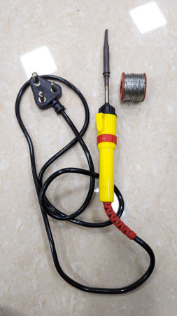an electric soldering tool with plug and solder metal wire on the floor used by students and...