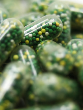 closeup macro shot of edible capsules with pills in green, yellow and white color containing...