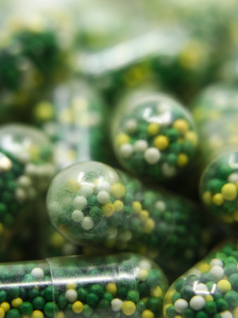 closeup macro shot of edible capsules with pills in green, yellow and white color containing vitamins and minerals used as nutritional supplementの写真素材