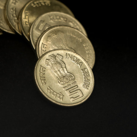 antique indian gold 5 (five) rupee coins arranged in a row shaped like a curve in closeup isolated...