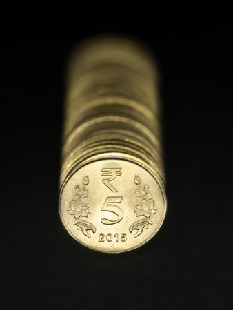 closeup of vintage 5 or five rupee gold coins of india arranged in a straight in a row isolated in a black backgroundの写真素材