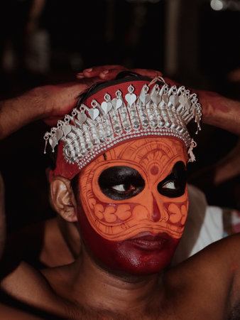 a closeup portrait of an artist with face paint makeup who performs theyyam, a traditional dance and art form that celebrates and worship hindu culture in kerala, Indiaのeditorial素材