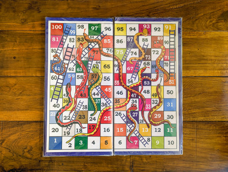 closeup of a colorful version of a snake and ladders multiplayer board game in a wooden table...