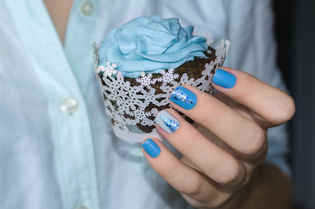 Cupcake in woman hand with sparkle blue manicureの写真素材