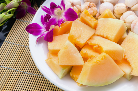 Sliced sunlady melon and mangostine on white plate with orchidの写真素材