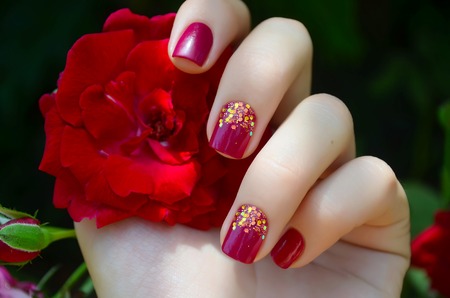 Woman hand with sparkle pink manicure and red flowerの写真素材