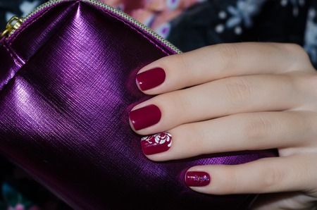 Woman hand with dark red nail design and purple bag for cosmeticsの写真素材