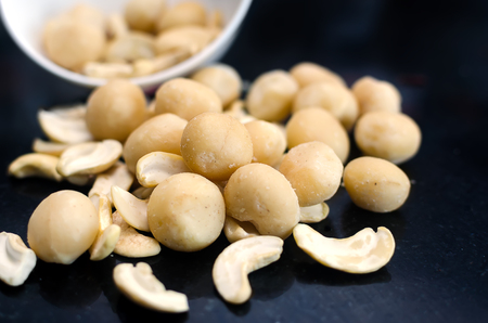 Mix of macadamia and cashew nuts on black tableの写真素材