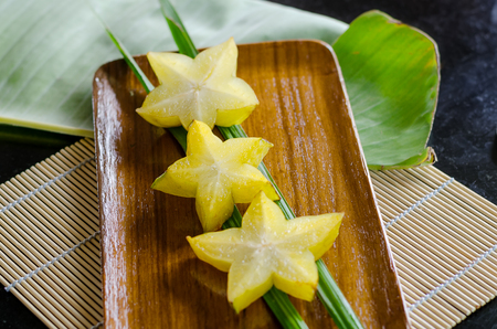 Sliced carambola fruit and palm leaf on wooden plateの写真素材