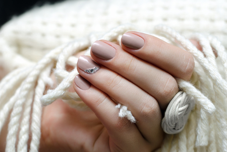 Beautiful female hand with warm beige nail design.の写真素材
