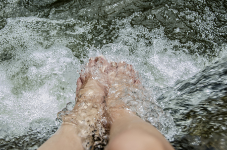 feet of a young woman refreshing under clear and cool water of the waterfall. Samui, Thailand.の写真素材