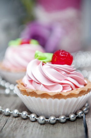 close-up of pink cupcake with icing on wooden table.の写真素材