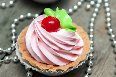 Close-up of pink cupcake with icing on wooden table.の写真素材