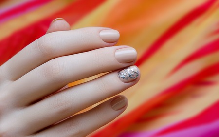 Beautiful female hand with warm beige nail design.の写真素材